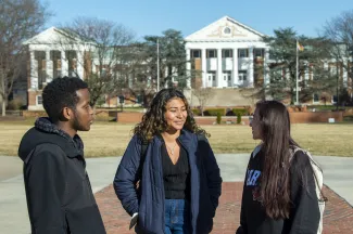 Three University of Maryland students chat with each other on campus